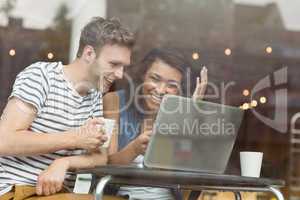 Smiling friends with a hot drink using laptop