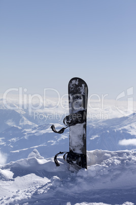 Snowboard in snow on off-piste slope at sun day