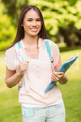 Portrait of a smiling student with a shoulder bag and holding bo
