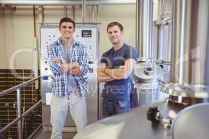 Young men with arms crossed smiling at camera