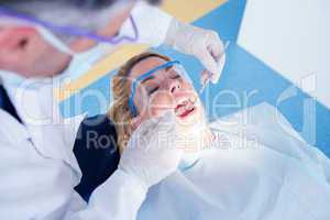 Dentist examining a patients teeth in the dentists chair