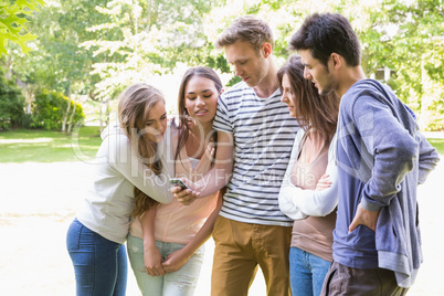 Happy students looking at smartphone outside on campus