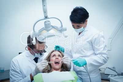 Dentist with assistant examining womans teeth