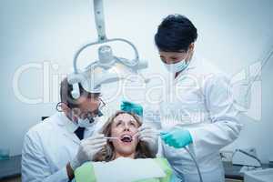 Dentist with assistant examining womans teeth