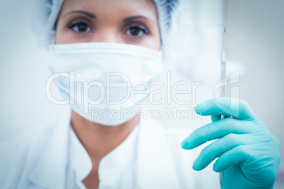 Female dentist in surgical mask holding hook