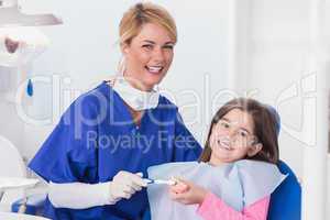 Smiling dentist teaching to her young patient how use toothbrush