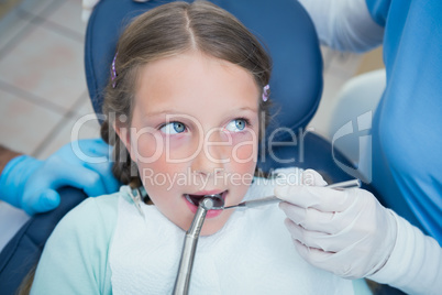 Dentist with assistant examining girls teeth