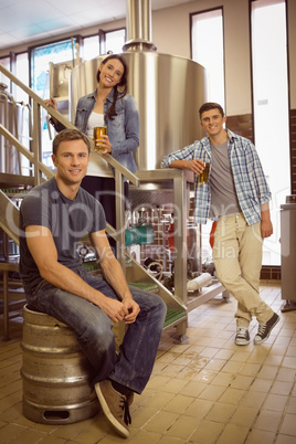 Man siting on keg and his colleague holding a glass of beer