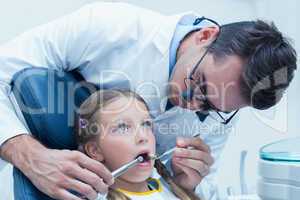 Male dentist examining girls teeth