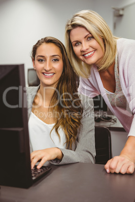 Smiling teacher and student behind desk at computer