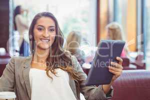 Student using digital tablet and holding disposable cup