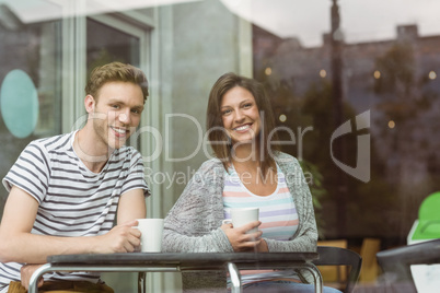 Smiling friends holding mug of coffee