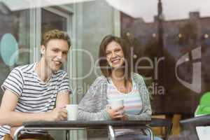 Smiling friends holding mug of coffee