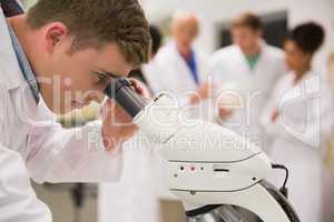 Young medical student working with microscope