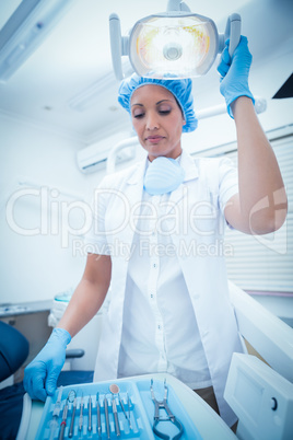 Serious female dentist adjusting light