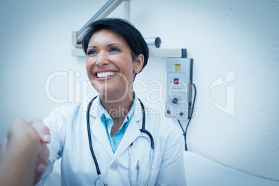 Cheerful dentist shaking hands with patient