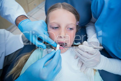 Dentist with assistant examining girls teeth