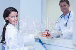 Smiling biologists with blood sample looking at camera