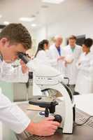 Young medical student working with microscope