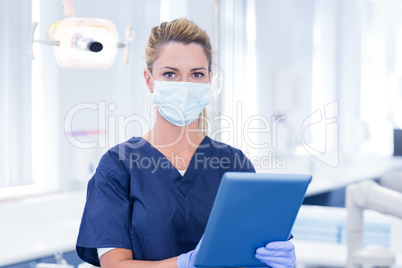 Dentist in mask using her tablet and looking at camera