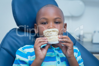 Portrait of smiling boy holding mouth model