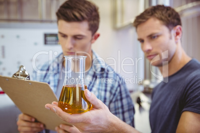 Two men looking at the beaker with beer