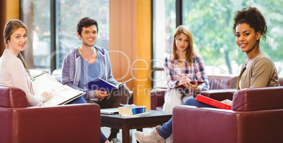 Students sitting on couch revising and smiling at camera