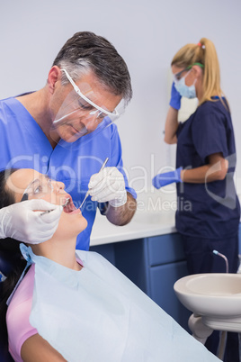 Dentist wearing face shield and examining a patient