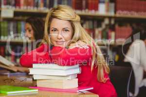 Smiling mature student leaning on a stack of books
