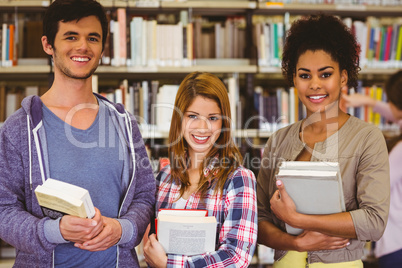 Students standing and smiling at camera holding books