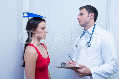 Confident doctor measuring patients height