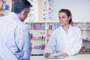 Trainee writing prescription in front of a customer