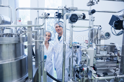 Scientist team behind metal gauge looking at camera