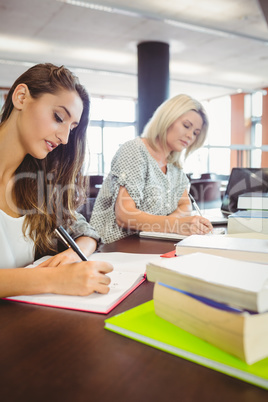 Matures females students writing notes at desk