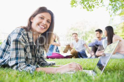 Happy student using her laptop outside