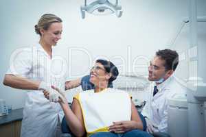 Male dentist with assistant shaking hands with woman