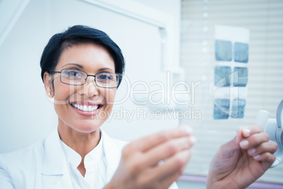 Happy female dentist holding x-ray