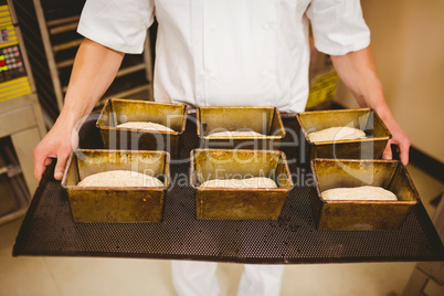 Baker holding tray of loaf tins