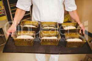 Baker holding tray of loaf tins