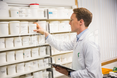 Handsome pharmacist taking medicine from shelf