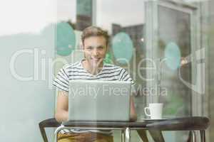 Smiling student using laptop in cafe