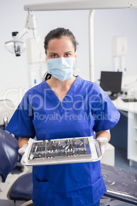 Portrait of a dentist with surgical mask and holding tray