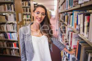 Pretty student picking out a book in library