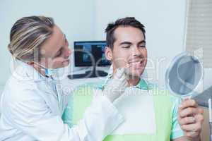 Female dentist examining mans teeth