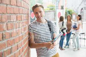 Handsome student smiling and holding notepads