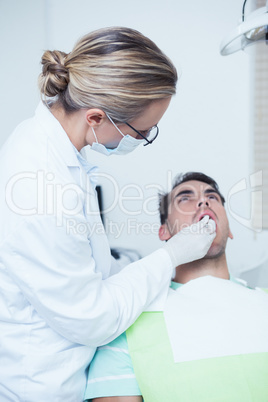 Female dentist examining mans teeth