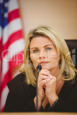 Portrait of a serious judge with american flag behind her