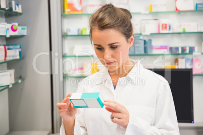 Junior pharmacist reading medicine box