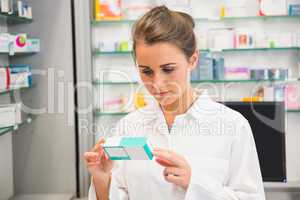 Junior pharmacist reading medicine box