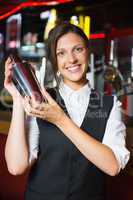 Happy barmaid smiling at camera making cocktail